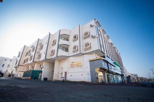 a large white building on the side of a street at الجوهرة البيضاء للشقق المخدومة in Taif