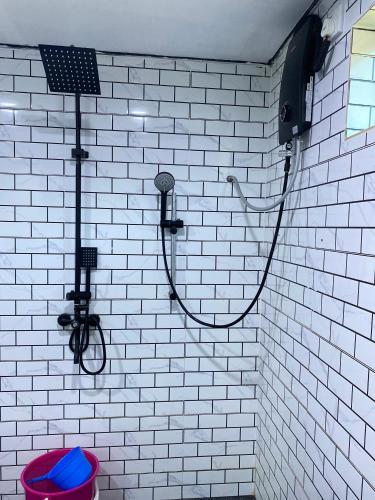a white tiled bathroom with a shower and a toilet at Abe cottage in Kampung Kuala Besut