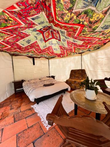 une chambre avec un lit et une table dans une tente dans l'établissement Les Cabanes du Vigné, à Molandier