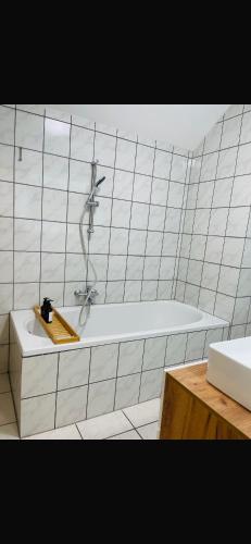 a white tiled bathroom with a tub and a sink at FeWo - Heinsberg-Dremmen in Heinsberg