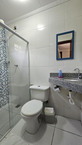 a white bathroom with a toilet and a shower at Pousada Recanto da Mata in Marechal Floriano