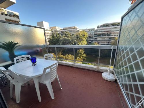 a white table and chairs on a balcony with a view at Le lys d'or Piscine Plage Terrasse Wiffi in Juan-les-Pins