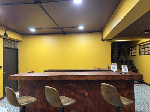 a bar in a room with yellow walls and chairs at Phoenix Room in Ban Tha Samet (1)