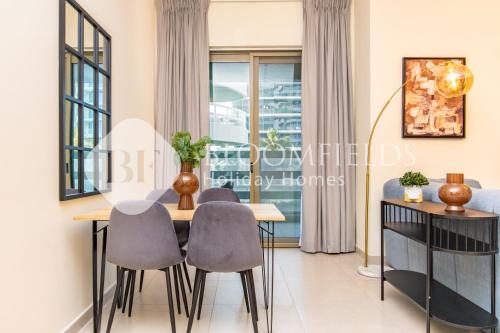 a dining room with a table and chairs and a window at Bloomfields Stylish 2br in Ajwan Soul Beach Access in Abu Dhabi