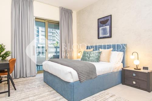 a bedroom with a blue bed and a desk at Bloomfields Stylish 2br in Ajwan Soul Beach Access in Abu Dhabi
