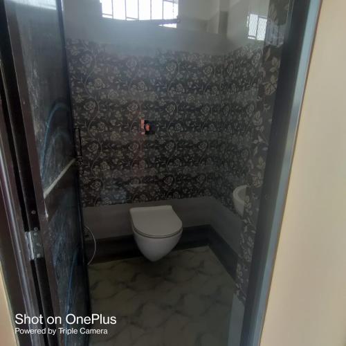 a small bathroom with a toilet and a window at Ashiyana Homestay in Patna