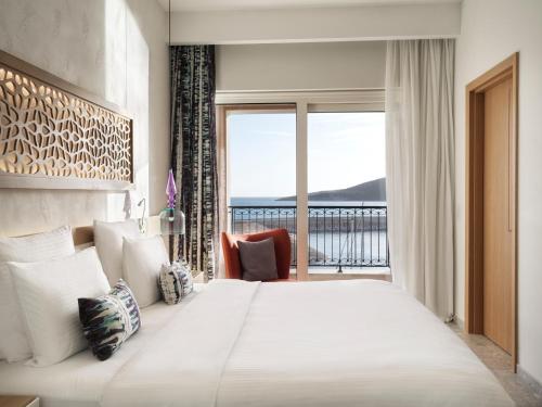 a bedroom with a large bed and a large window at The Chedi Luštica Bay in Tivat