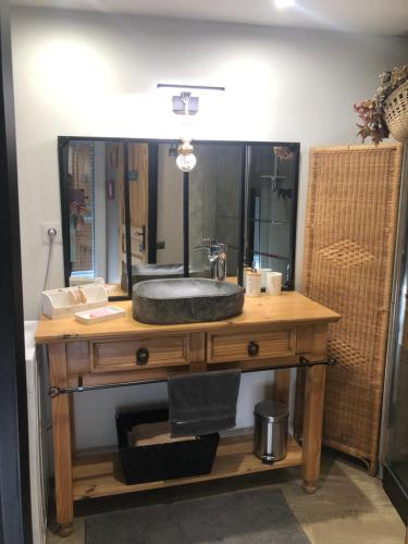 une salle de bain avec un lavabo et un grand miroir dans l'établissement l'atelier de Sophie, à Longueville