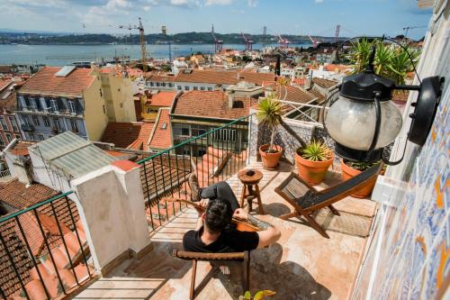 a man sitting on a chair on a balcony looking at the city at Olympo Shared flat with Amazing River view in Lisbon