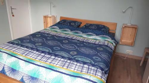 a bed with a blue and white comforter on it at Le Coeur sur la Main in Namur