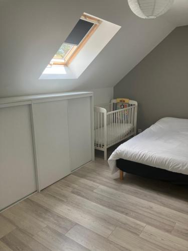 une chambre avec un berceau et un lit avec une lucarne dans l'établissement Maisonette proche mer, à Saint-André-des-Eaux