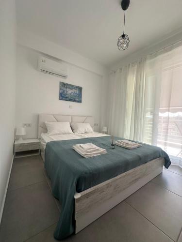 Un dormitorio blanco con una cama grande con una manta azul. en Palm Complex Calma Di Mare Apartment, en Ofrinion