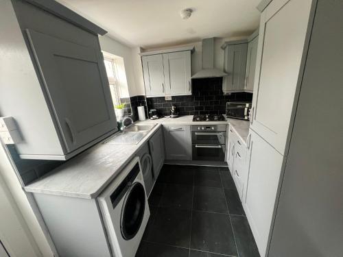 a kitchen with white cabinets and a washer and dryer at Cardiff Gate Lodge in Cardiff