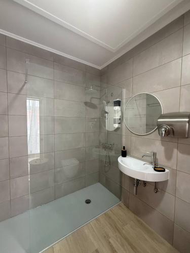 ein Badezimmer mit Dusche, Waschbecken und Spiegel in der Unterkunft Cidade Mar in Horta