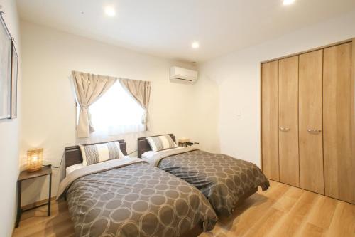 a bedroom with two beds and a window at ほんだけ in Ishigaki Island