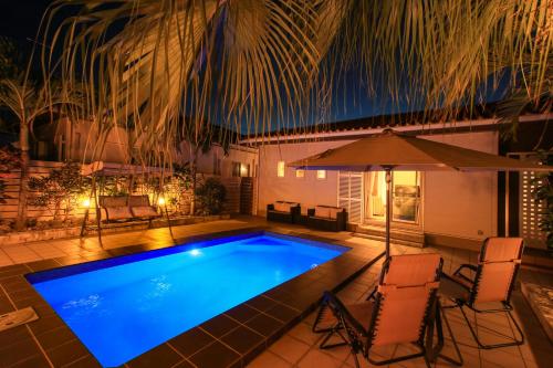 una piscina con sedie e un ombrellone di ほんだけ a Isola di Ishigaki