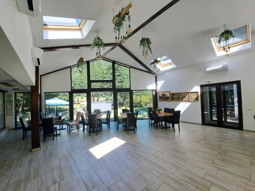 a large room with tables and chairs and windows at Moara Viselor in Vaideeni