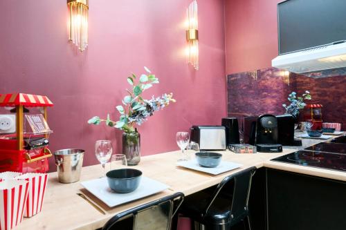 a kitchen with a counter with a table with chairs at Le Cinema - Les Demeures d'Adrien in Armentières