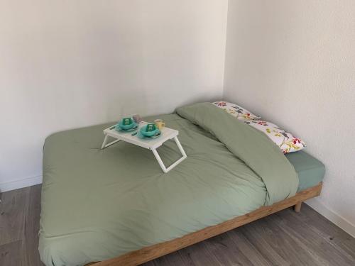 La Celle-sous-GouzonにあるStudio vert idéalement situé gare cœur de ville et accès direct bus futuroscopeのベッド(小さなテーブル付)