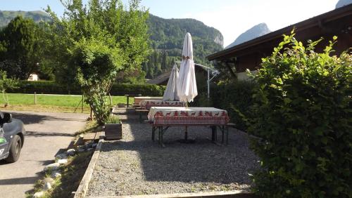 a patio with a table and an umbrella in a yard at Particulier loue 2 appartements communicants dans chalet à Samoëns jusqu à 16 couchages in Samoëns