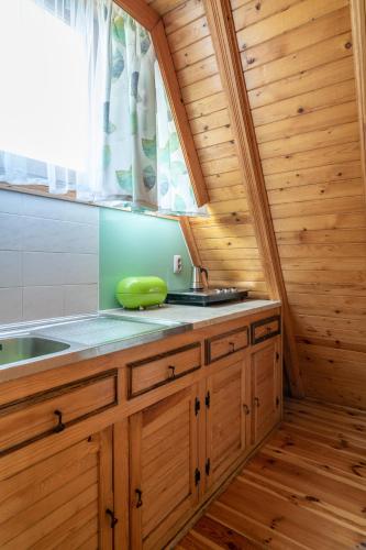 a kitchen with wooden cabinets and a sink and a window at Domki letniskowe w lesie nad jeziorem - Kaszuby, Ośrodek Wczasowy KLIF in Wdzydze Kiszewskie