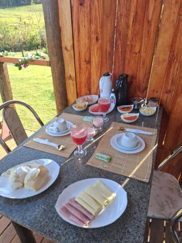 a table with plates of food and glasses of wine at Chalés Refúgio no Campo in Santo Antônio do Pinhal