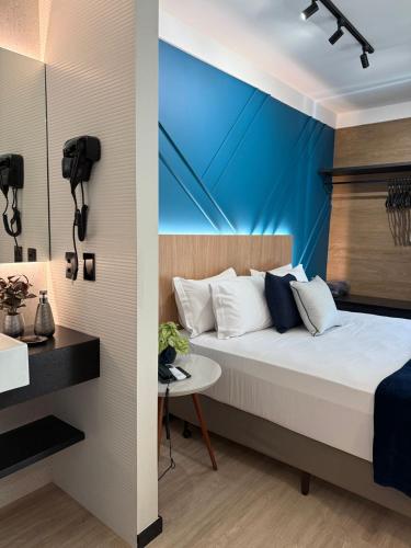 a bedroom with a bed and a blue wall at Flat Blue Praia de Camburi in Vitória