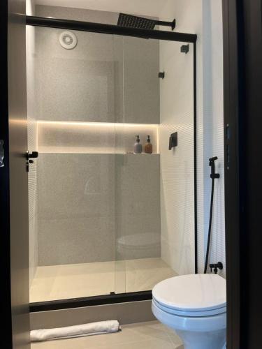 a glass shower in a bathroom with a toilet at Flat Blue Praia de Camburi in Vitória