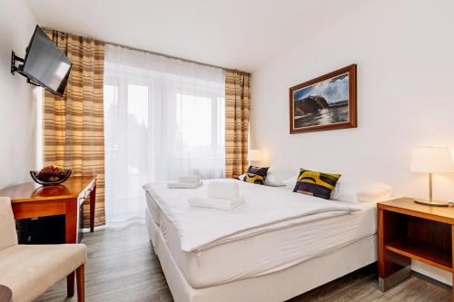 a bedroom with a large white bed and a desk at Hotel Marttel in Karlovy Vary