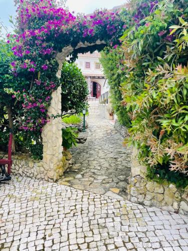 an alley with purple flowers on a stone path at Alto Paraíso Boutique Hotel in Reguengo Grande