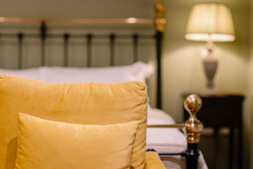 a bed with a yellow pillow and a lamp at The Crown, Bildeston in Bildeston