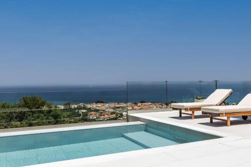 a pool on the roof of a house with two lounge chairs at Melody Blue Villa in Argassi