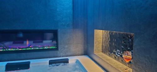 a bathroom with a tub with a fireplace and a glass of wine at Siedmiu Króli Rooms&SPA in Bukowina Tatrzańska