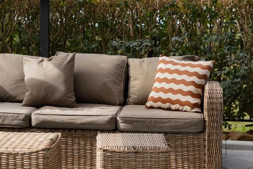 a wicker couch with pillows on a patio at The Lake Haus - Spacious Waterfront Escape with Pool in Karraganbah