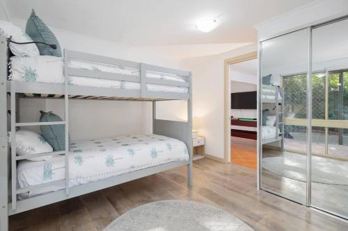 a bedroom with two bunk beds and a mirror at The Lake Haus - Spacious Waterfront Escape with Pool in Karraganbah