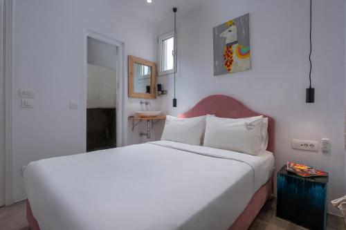 a bedroom with a white bed and a sink at Flaskos Luxury Suites in Agios Stefanos