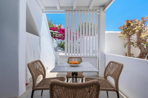 a table and chairs with a bowl of fruit on a balcony at Flaskos Luxury Suites in Agios Stefanos