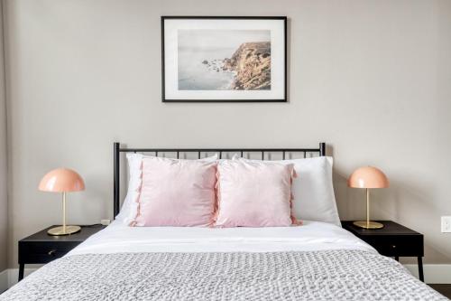 een slaapkamer met een bed met roze kussens en 2 lampen bij Blueground Mountain View pool nr Shoreline Park SFO-1324 in San Francisco