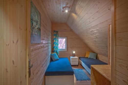 a small room with a blue couch in a wooden house at Domki letniskowe w lesie nad jeziorem - Kaszuby, Ośrodek Wczasowy KLIF in Wdzydze Kiszewskie