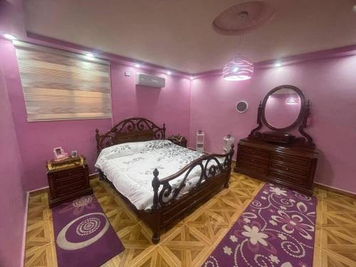 a bedroom with a bed and a mirror and purple walls at Luxury couple room in irbid in Irbid