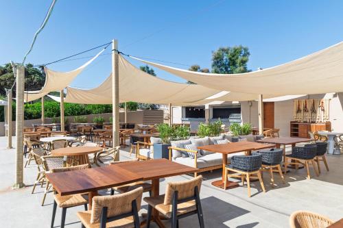 a patio with wooden tables and chairs and a canopy at Mangia's Sardinia Resort - NEW OPENING in Santa Teresa Gallura