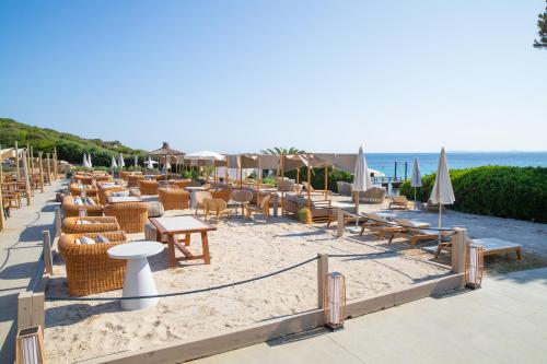 a sandy beach with chairs and tables and umbrellas at Mangia's Sardinia Resort - NEW OPENING in Santa Teresa Gallura