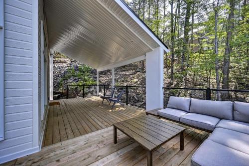 a porch with a couch and a table on a deck at Kensho Enjoy nature life with Hot tub in Sainte Béatrix