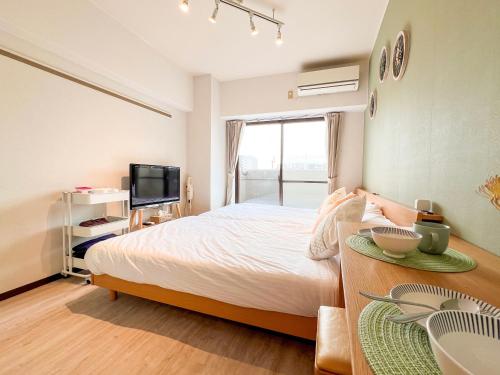 a bedroom with a bed and a table and a tv at Direct 6min to Nagoya Sta Max4ppl 1BDR Wi-Fi in Aoichō