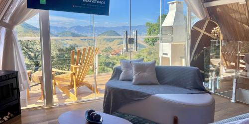 a living room with a couch and a large window at Chalés Quinta da Boa Vista in São Bento do Sapucaí