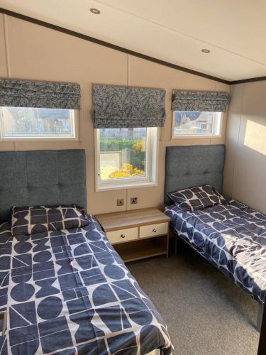 a bedroom with two beds and two windows at Parkview holiday lodge in Lossiemouth
