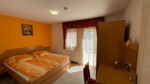 a bedroom with a bed and a table and a window at Andrea Apartmanok in Zalakaros