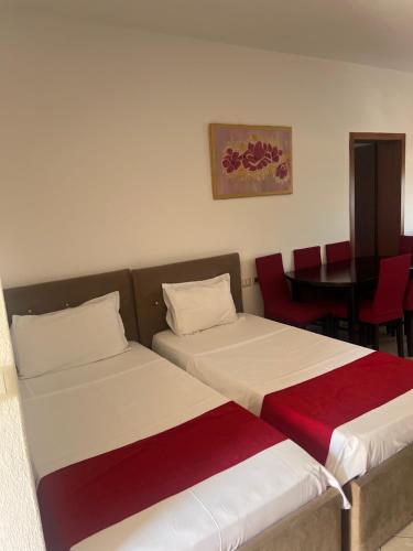 two beds in a room with a table and chairs at Hotel Gjoci in Shëngjin