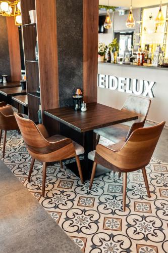 a table and chairs on a tile floor in a restaurant at Hotel Heidelux in Soltau