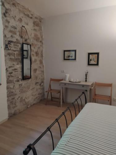 a bedroom with a bed and a table and a stone wall at Casa del Vicolo in Ome